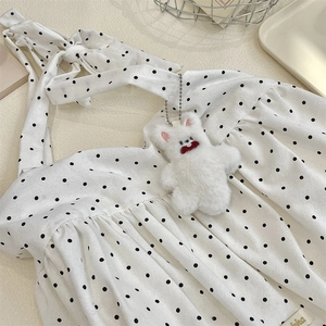 Detail of white polka dot halter top with a cute plush bear charm on a metal tray