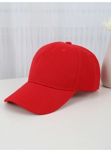 Close-up of a red cotton baseball cap on a white table with a clean minimalist background