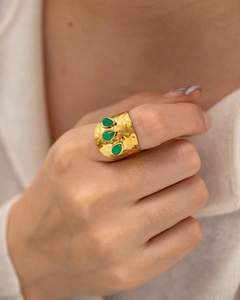 Détail d'une bague martelée dorée avec trois pierres vertes en forme de goutte