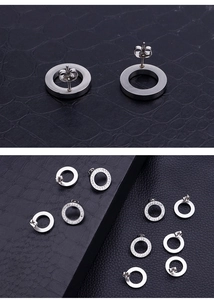 Detailed view of polished and zircon-encrusted stainless steel stud earrings on black texture