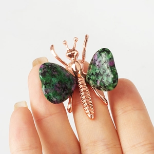 Rose gold butterfly ornament with ruby zoisite stone wings on a white background