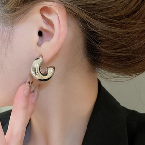 Close-up of minimalist silver C-shaped chunky hoop earrings with polished finish on model