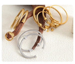 Gros plan détaillé de bracelets torsadés en or et argent sur une branche naturelle