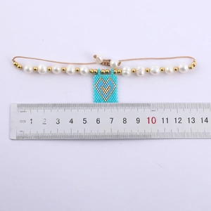 Bohemian heart charm bracelet with freshwater pearls and gold beads on a ruler