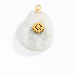 Detailed macro view of white natural stone pendant with gold sun pattern and bail