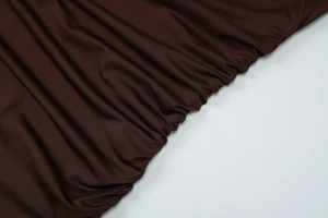 Detail of ruched dark brown knit fabric with elastic texture on an off-shoulder dress