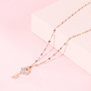 Macro shot of rose gold key pendant with white shell inlay and delicate link chain