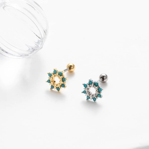 Detail view of gold and silver screw earrings with round turquoise stone inlay on white