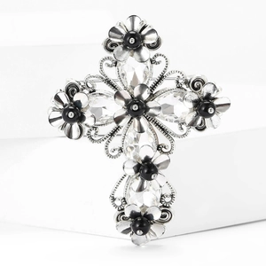 Vintage silver cross brooch with crystals and black floral beads on a white pedestal
