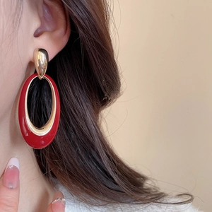 Macro view of vintage style red enamel and gold-plated heart earrings on ear