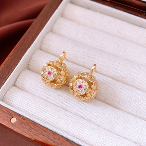 Macro detail of vintage gold hollow ball earrings with rose red center gemstones