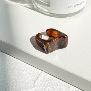 Detailed view of amber resin ring with unique irregular design on textured background
