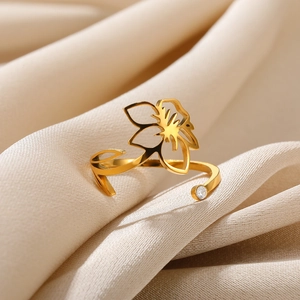 Detailed close-up of golden stainless steel flower ring with zircon on silk fabric