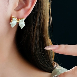 Détail de la boucle d'oreille nœud plaqué or 14K avec fini nacré blanc sur le mannequin