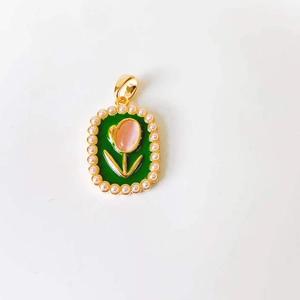 Close-up of golden tulip pendant with green enamel, pink flower bud and pearl trim