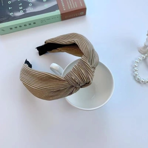 Serre-tête plissé à nœud beige doré présenté sur une tasse décorative élégante