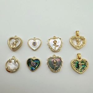 Detail view of 18K gold plated heart and round shell charms with rabbit and flower patterns