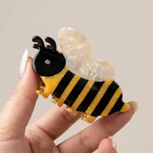 Detail of bee hair claw clip featuring yellow stripes and sparkling white rhinestone