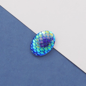 Detailed view of oval resin flatback with blue-green gradient fish scale pattern