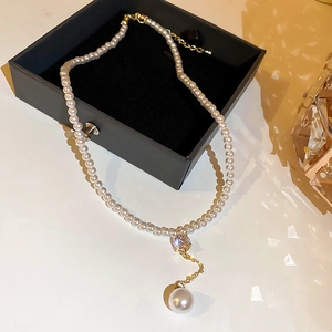 Détail d'un collier de perles vintage avec fermoir doré et pendentif en diamant