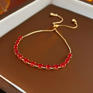 Detail of gold bolo bracelet with red oval zircons in a brown jewelry gift box