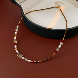 Detail of beaded necklace featuring tiger eye stones, freshwater pearls, and red agate
