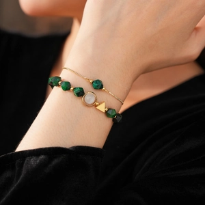 Detail of beaded tiger eye bracelets featuring green malachite beads and golden metal charms