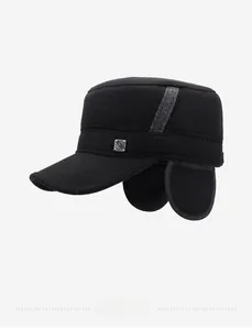 Detail of black winter flat top hat with foldable ear flaps and metal fashion logo