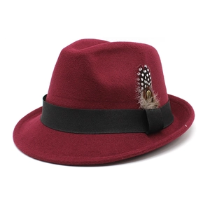 Detail of burgundy wool fedora featuring a black ribbon band and elegant spotted feather