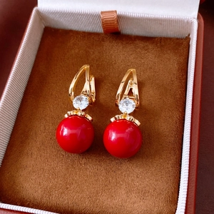 Close-up of vintage style earrings with red resin beads and zircons on velvet