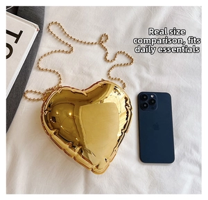 Size comparison of a gold heart-shaped mini bag with a pearl chain next to a smartphone