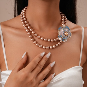 Détail d'un collier de perles à double rangée avec fleur ornée de cristaux bleus