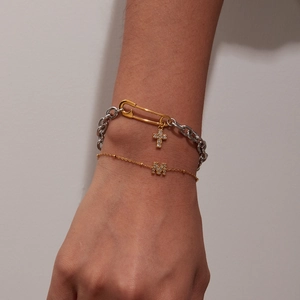 Detail of layered titanium bracelets with pin cross and zircon M letter charms