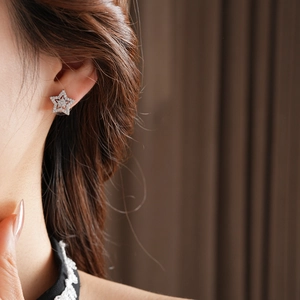 Detailed close-up of a silver star stud earring with shimmering pavé zircon stones
