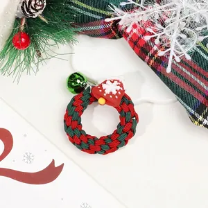 Close-up of a festive Christmas scrunchie with a green bell and snowflake pendant charm
