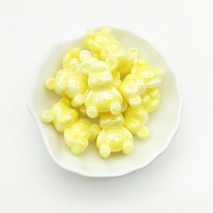 Macro shot of yellow pearlescent bear beads in a white petal dish for DIY jewelry