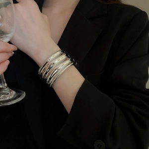 Close-up of wide silver ripple bangle with liquid metal texture on a model's wrist