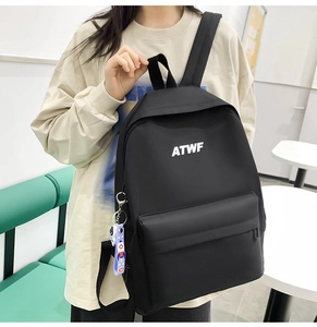 Detail of black nylon backpack with ATWF logo and purple rocket pendant held by hand