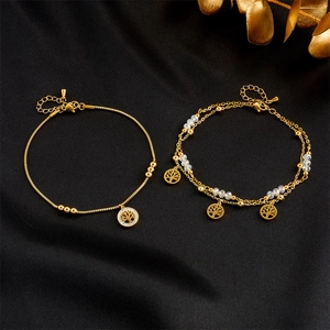 Detailed close-up of gold titanium steel tree of life anklets on black silk background
