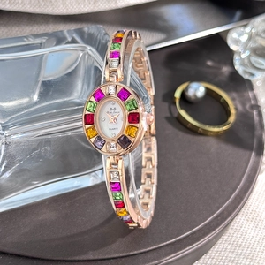 Detail of rose gold quartz watch featuring colorful square gemstones and oval dial display