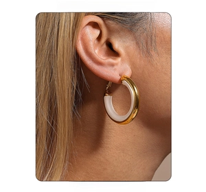 Detail of model wearing oversized 18K gold and white enamel hoop earrings for women