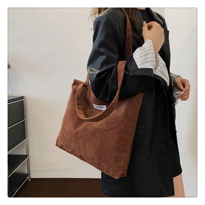 Detail of a brown corduroy tote bag featuring a stitched white FASHION letter label