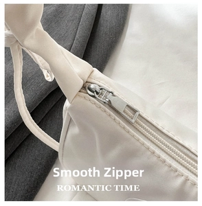 Detail shot of a smooth silver metal zipper on a white nylon shoulder bag fabric