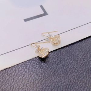 Detail of gold bow earrings with zircon stones and fan-shaped shell pendant detail