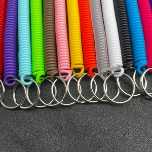 Portachiavi a spirale colorati in plastica con anelli metallici su sfondo grigio