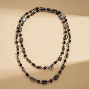 Detail showing layered long necklace with shell plates and dark crystal beads