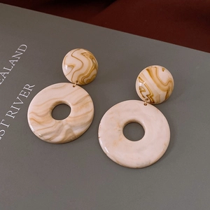 Close-up of beige marble resin geometric earrings on a magazine with natural lighting