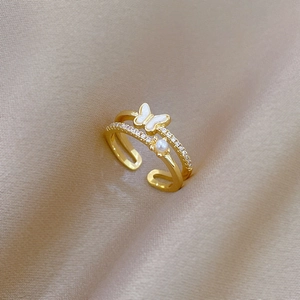 Détail macro d'une bague papillon dorée avec perle et zircone sur de la soie