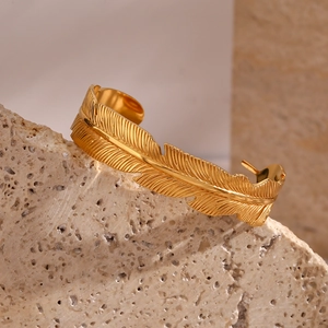 Macro detail of 18K gold-plated stainless steel leaf bracelet on natural stone