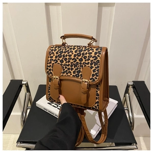 Detail of a brown leopard print backpack with faux leather straps and vintage gold buckles